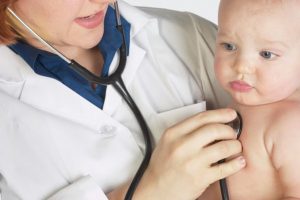 Doctor holding and monitoring baby with stethoscope